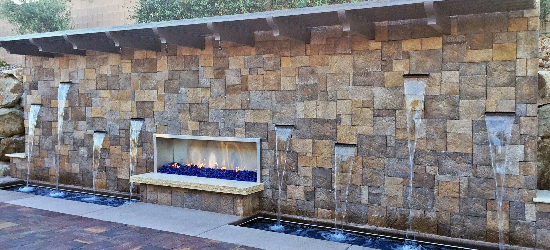 Beautiful stone wall with small waterfalls and a gas fireplace in the middle